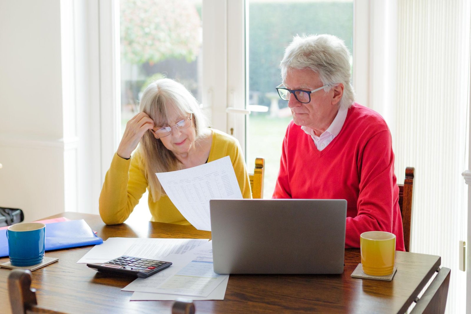 Older British couple reviewing household bills and State Pension paperwork at home.